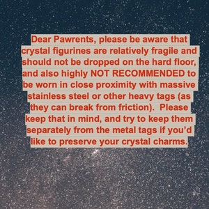 May include: A text-based image with a message about crystal figurines. The message reads: "Dear Pawrents, please be aware that crystal figurines are relatively fragile and should not be dropped on the hard floor, and also highly NOT RECOMMENDED to be worn in close proximity with massive stainless steel or other heavy tags (as they can break from friction). Please keep that in mind, and try to keep them separately from the metal tags if you'd like to preserve your crystal charms."