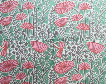 Op de afbeelding: Een groene stof met een herhalend patroon van roze en rode bloemen en grijze stelen. De stof heeft een vintage, handbedrukte uitstraling.