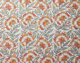 Op de afbeelding: Witte stof met een herhalend patroon van oranje, rode en witte gestileerde bloemen met groene bladeren.