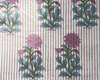 Op de afbeelding: Witte stof met roze en blauwe bloemenprint. De stof heeft dunne roze strepen.