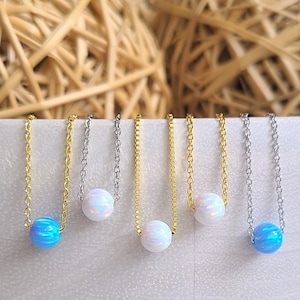May include: Six delicate necklaces with a single opal bead on each. The necklaces are available in silver and gold chains. The opal beads are white and blue.