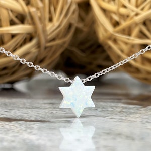 May include: A silver chain necklace with a white opal Star of David pendant.
