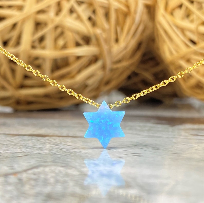 May include: A gold chain necklace with a blue opal Star of David pendant.