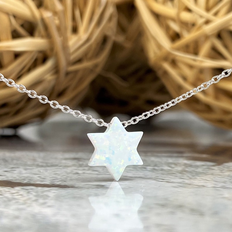 May include: A silver chain necklace with a white opal Star of David pendant.