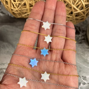 May include: Six delicate necklaces with a star of David pendant. Each necklace features a different color opal stone, including white and blue.