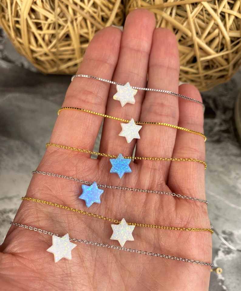 May include: Six delicate necklaces with a star of David pendant. Each necklace features a different color opal stone, including white and blue.