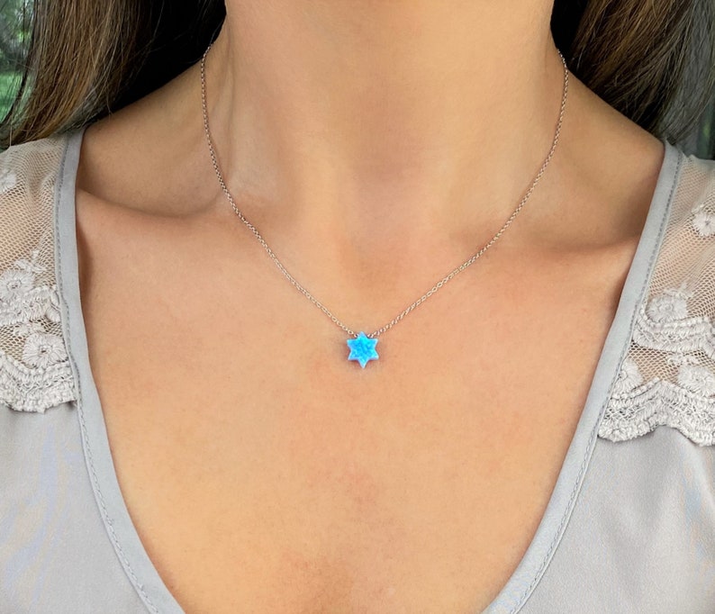 May include: A silver chain necklace with a blue opal Star of David pendant.