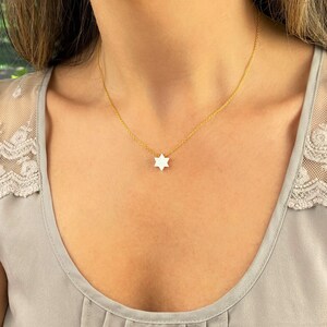 May include: A delicate gold chain necklace with a small white star of David pendant.