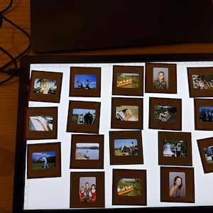 May include: A collection of vintage 35mm slides illuminated on a light table. The slides depict various scenes, including people, landscapes, and events, offering a glimpse into the past. The slides are in brown cardboard frames.