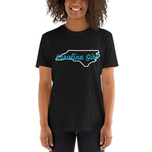 May include: Black t-shirt with a white outline of the state of North Carolina and the text "Carolina Girl" in blue.