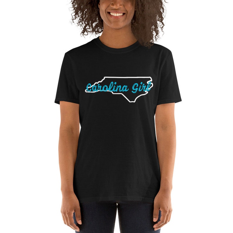May include: Black t-shirt with a white outline of the state of North Carolina and the text "Carolina Girl" in blue.