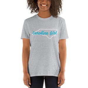 May include: A heather grey t-shirt with a white outline of the state of North Carolina and the text "Carolina Girl" in blue.
