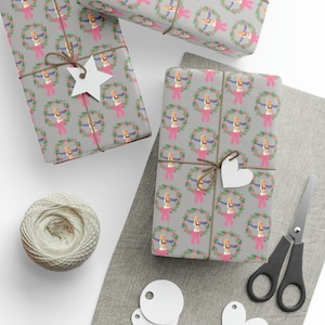 Könnte beinhalten: Drei graue Geschenkboxen mit einem sich wiederholenden Muster einer Frau in einem rosa und blauen Outfit, die einen Kranz hält. Die Boxen sind mit Schnur umwickelt und mit weißen Papiersternen und Herzen verziert.