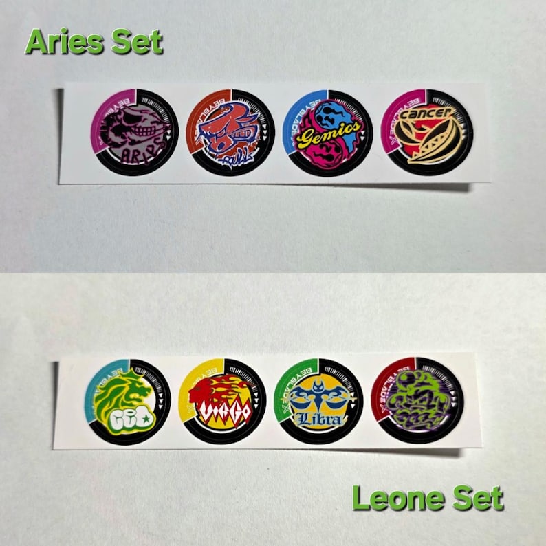 Pu&ograve; includere: Un set di otto adesivi circolari colorati con segni zodiacali. La riga superiore recita "Aries Set" e include adesivi con i segni Ariete, Toro, Gemelli e Cancro. La riga inferiore recita "Leone Set" e include adesivi con i segni Leone, Vergine, Bilancia e Scorpione.