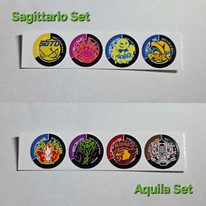 Pu&ograve; includere: Due serie di adesivi circolari, ciascuna su una striscia bianca. Il set superiore, etichettato "Sagittario Set", presenta disegni gialli, rosa e blu. Il set inferiore, etichettato "Aquila Set", presenta disegni rossi, viola e marroni. Ogni adesivo ha una grafica unica.