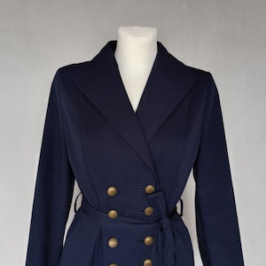 May include: A navy blue double-breasted coat with gold buttons and a belt.