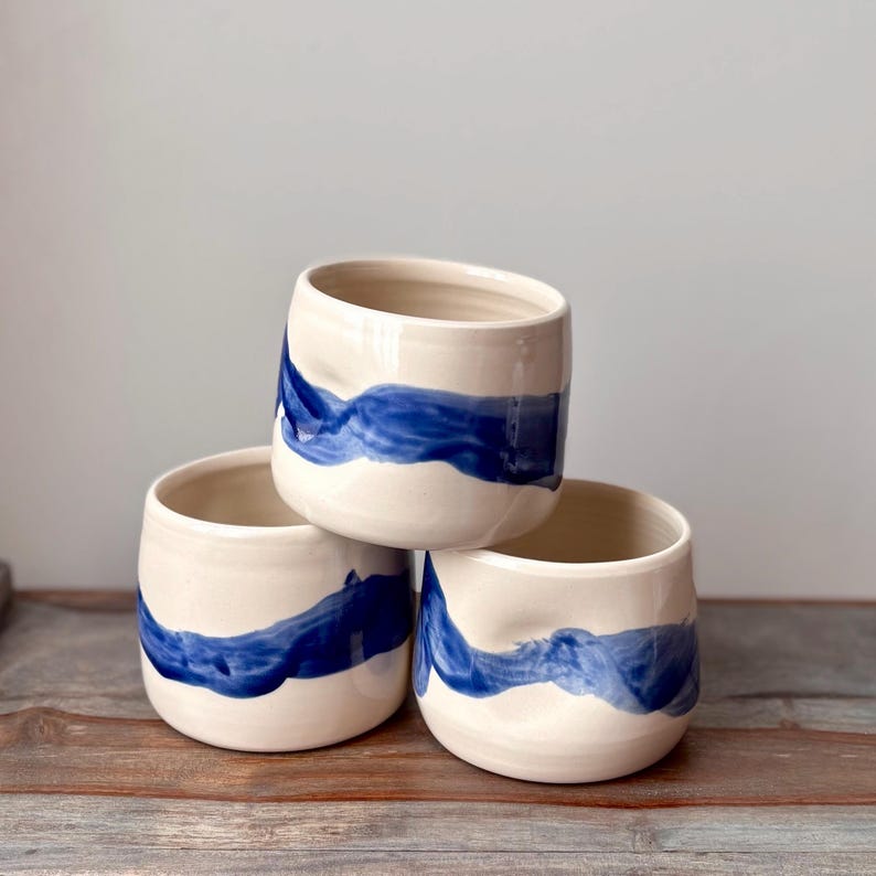 Cup with dimple in side for thumb and bold, wavy, blue brush stroke design