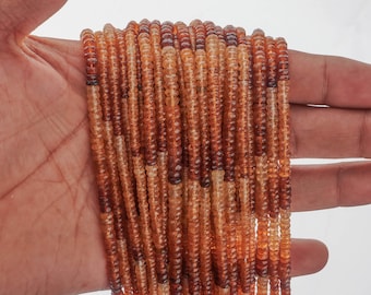May include: A strand of orange and brown gemstone beads. The beads are faceted and have a slightly irregular shape. The strand is approximately 16 inches long.