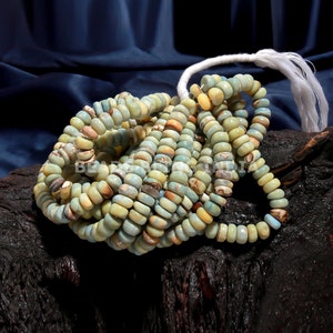 May include: A strand of light blue and yellow shell beads with a white tassel. The beads are round and have a smooth, polished finish.
