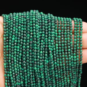 May include: A strand of green malachite beads, each bead is faceted and has a round shape.
