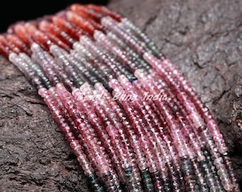 May include: A strand of pink, red, and green gemstone beads. The beads are faceted and have a variety of shapes and sizes. The beads are strung on a clear thread and are arranged in a random pattern.