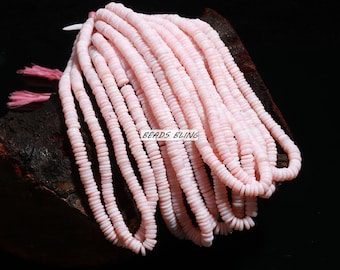 Op de afbeelding: Een streng roze opaal kralen, elke kraal is rond en licht afgeplat. De kralen zijn in een losse stapel gerangschikt, waarbij sommige kralen elkaar overlappen. De kralen zijn lichtroze van kleur, met een lichte iriserende glans.