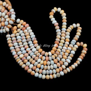 May include: A strand of multi-colored agate beads, with shades of white, orange, and brown. The beads are oval shaped and have a smooth, polished finish.