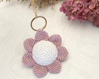 Könnte beinhalten: Ein rosa und weißer gehäkelter Blumen-Schlüsselanhänger mit einem goldenen Schlüsselring.
