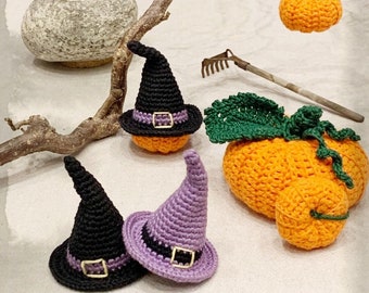 May include: Three crocheted pumpkins, one with a green stem and leaves, and two with black witch hats. One hat is purple and the other is black.
