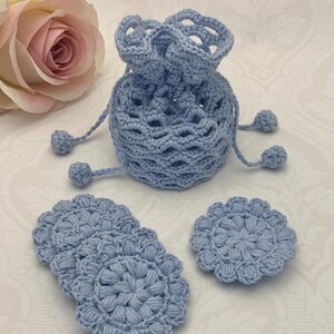 Puede incluir: Un conjunto de cuatro rondas de algod&oacute;n de crochet azul claro y una bolsa de cord&oacute;n de crochet azul claro con pompones.