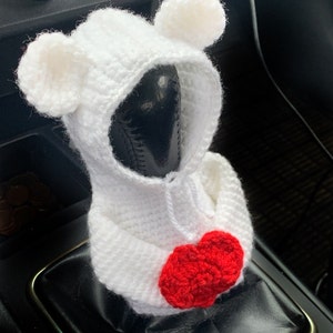 May include: White crocheted bear-shaped car gear shift cover with a red crocheted heart on the front.