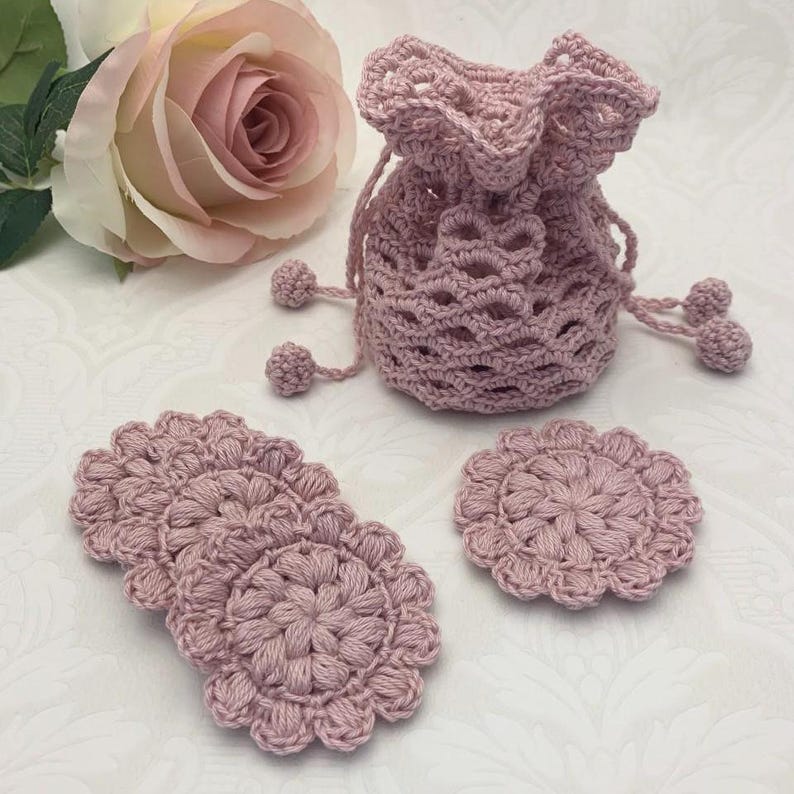 Puede incluir: Tres posavasos de ganchillo rosa y una bolsa de cord&oacute;n de ganchillo rosa con pompones.
