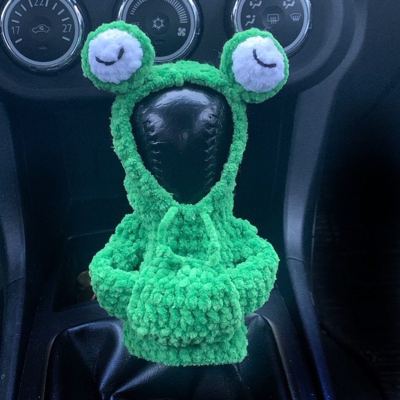Pu&ograve; includere: Copri leva del cambio del cambio in crochet verde a forma di rana con occhi bianchi.