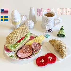May include: Crochet amigurumi pattern for a breakfast themed set including a croissant, a sandwich, a cup of tea, eggs, and a plate of sliced salami. The pattern is available as a PDF download.
