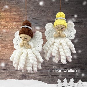 May include: Two crocheted angel ornaments with white wings and spiral skirts. One angel has brown hair, the other has yellow hair, both with silver headbands and hands in prayer. The text ellenKantarellen is visible at the bottom right.