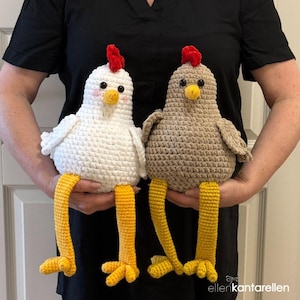 May include: Two crocheted chicken plushies. One is white, the other is brown. Both have red combs, yellow beaks and legs. The white chicken has pink cheeks. The chickens are handmade and have a whimsical design.
