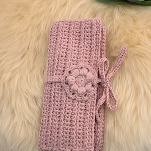 Puede incluir: Una manta de ganchillo rosa con un dise&ntilde;o de flores y un cierre de lazo.