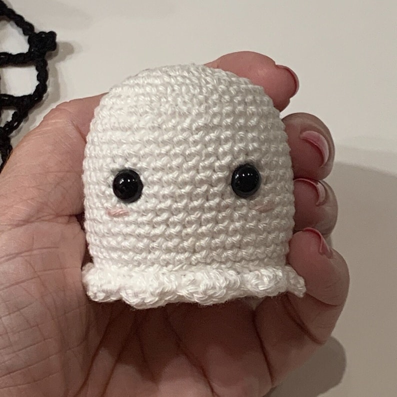 Puede incluir: Un peque&ntilde;o fantasma blanco tejido a ganchillo, con grandes ojos negros y mejillas rosadas. El fantasma hecho a mano tiene un cuerpo redondeado y un borde inferior con volantes. Este art&iacute;culo con tem&aacute;tica de Halloween es una decoraci&oacute;n linda y caprichosa.
