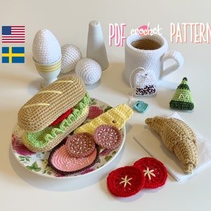 May include: Crochet amigurumi pattern for a breakfast themed set including a sandwich, croissant, eggs, coffee cup, and tea bag. The pattern is available as a PDF download.