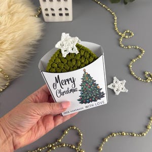 Peut inclure: Un objet fait main en forme de sapin de Noël, en fil vert, surmonté d'une étoile blanche. Il est présenté dans une boîte blanche avec une illustration de sapin de Noël et le texte "Merry Christmas".