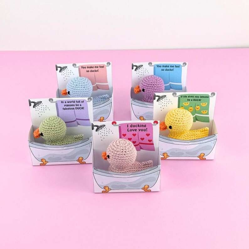 Puede incluir: Cuatro peque&ntilde;os patos de crochet en diferentes colores, cada uno en una caja de ba&ntilde;era blanca con un mensaje diferente en el frente. Los mensajes son: "You make me feel so ducky!" "In a world full of pigeons be a fabulous DUCK!" "I ducking Love you!" y "If life gives you lemons be a DUCK!"