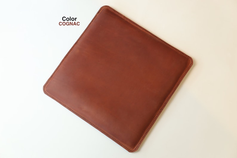May include: A cognac-colored leather laptop sleeve with a stitched edge.
