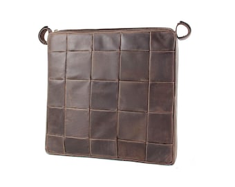 May include: A square dark brown leather bag featuring a grid-like pattern of stitched leather squares. The bag has a top zip closure and two small circular leather loops attached to the upper corners on both the left and right sides.