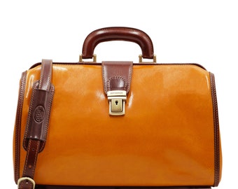 May include: A brown leather doctor's bag with a brass lock and a brown leather shoulder strap. The bag has a brown leather handle and a gold metal nameplate that reads "Dopprenze".