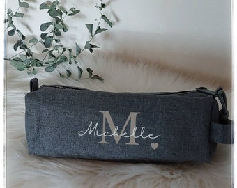 May include: A gray zippered pencil case with a personalized inscription that reads "Michelle" with a large "M" and a small heart.