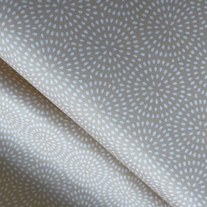 May include: Beige fabric with a white repeating pattern of small circles radiating outward from a center point.