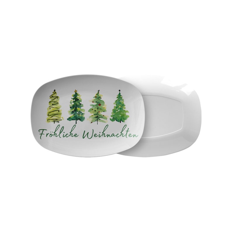 May include: White rectangular serving platter with a watercolor design of four green Christmas trees. The words "Fr&ouml;hliche Weihnachten" are written in green script below the trees. A second, identical platter is visible.