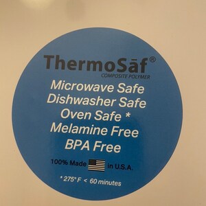 May include: A close-up of a white surface with a blue circular sticker. The sticker reads "ThermoSaf Composite Polymer" and lists features like "Microwave Safe" and "BPA Free." It also states "100% Made in U.S.A."