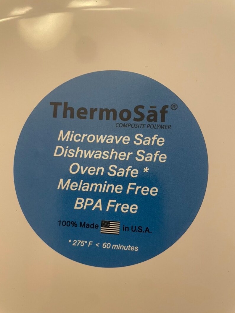 May include: A close-up of a white surface with a blue circular sticker. The sticker reads "ThermoSaf Composite Polymer" and lists features like "Microwave Safe" and "BPA Free." It also states "100% Made in U.S.A."