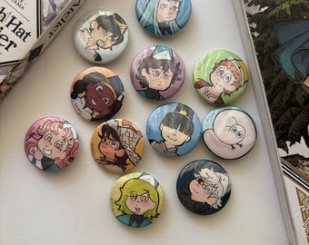 Puede incluir: Una colección de diez chapas redondas con ilustraciones de personajes al estilo anime de la serie de manga Witch Hat Atelier. Cada chapa muestra un retrato de personaje único con colores de pelo, expresiones faciales y atuendos distintos.